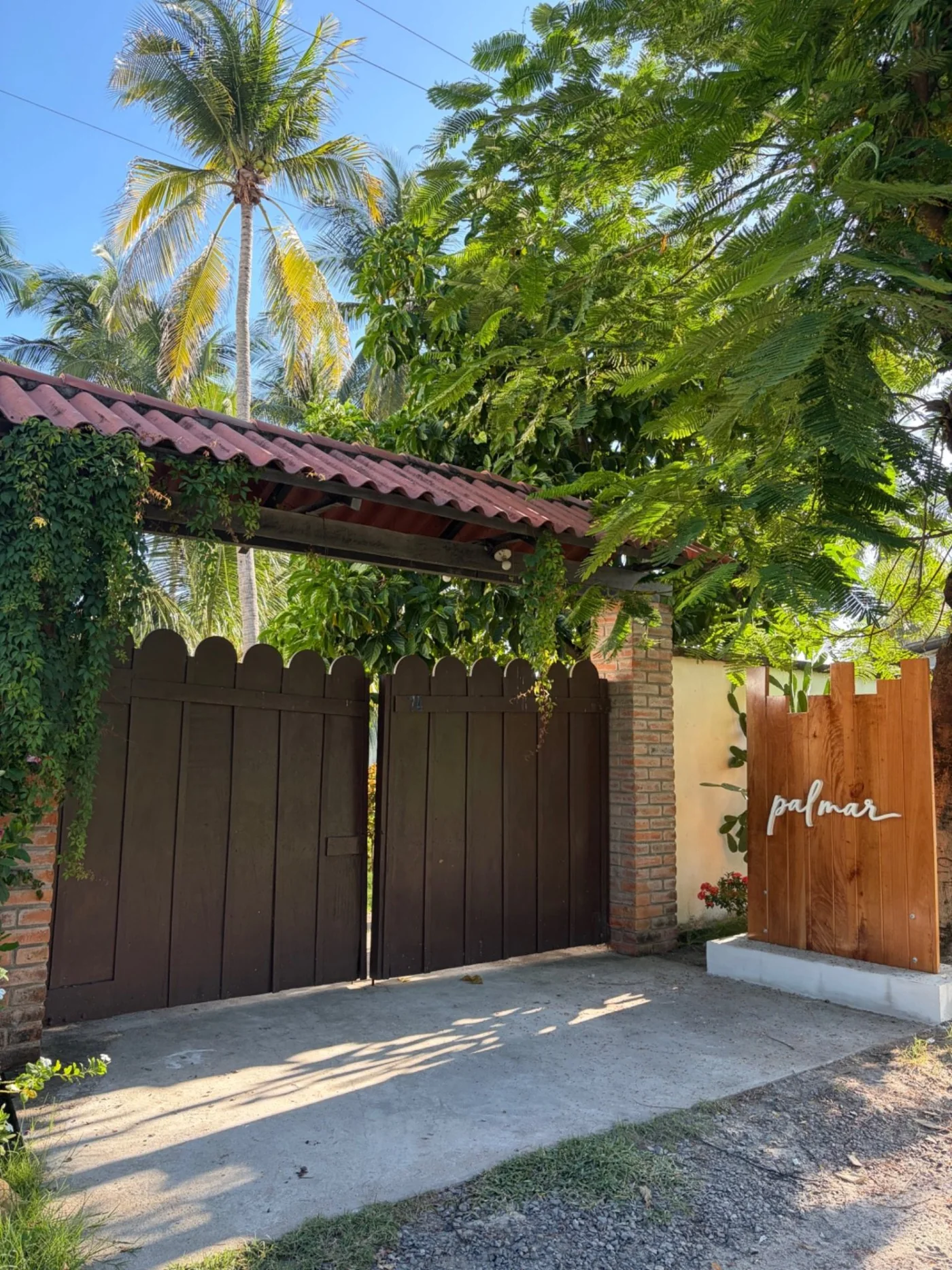 Entrada real de Rancho Palmar entre vegetación tropical, con el rótulo Palmar visible