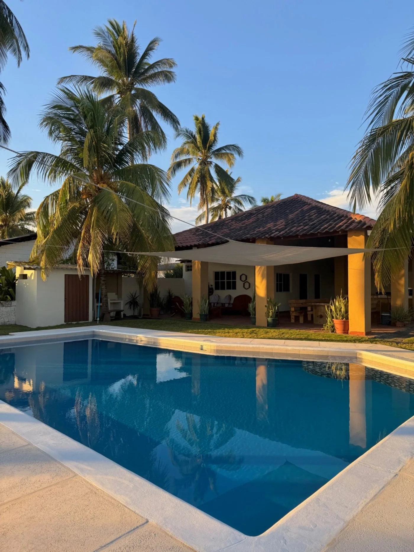 Piscina y casa de Rancho Palmar iluminadas por la luz cálida del atardecer