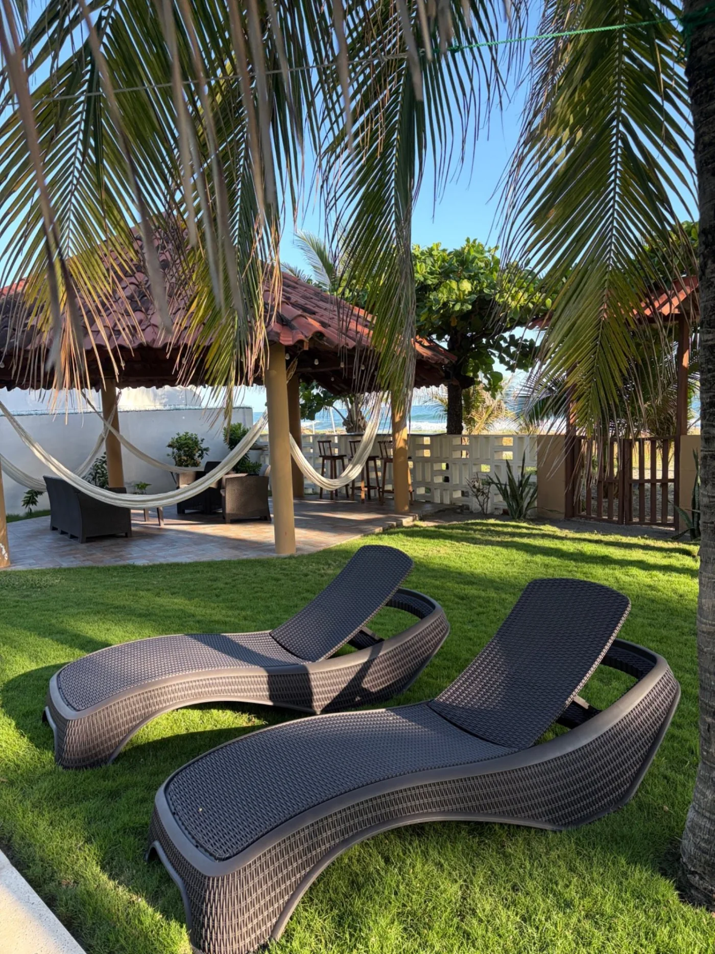 Reposeras sobre el jardín tropical junto a la palapa de Rancho Palmar